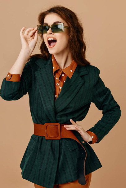 συναισθηματική γυναίκα με κοστούμι με ανοιχτό στόμα γυαλιά ηλίου μπεζ φόντο - Φωτογραφία, εικόνα