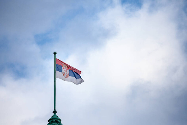 Foto della bandiera ufficiale della Repubblica di Serbia, con uno sfondo di cielo blu e nuvole. La Serbia è una nazione dei Balcani, in Europa - Foto, immagini
