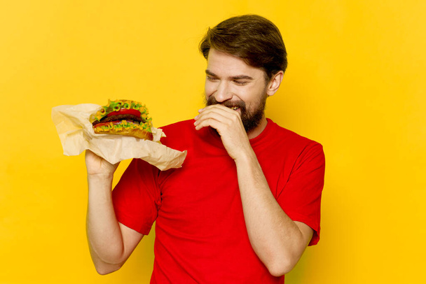 szakállas férfi piros pólóban hamburger gyorsétterem diéta - Fotó, kép