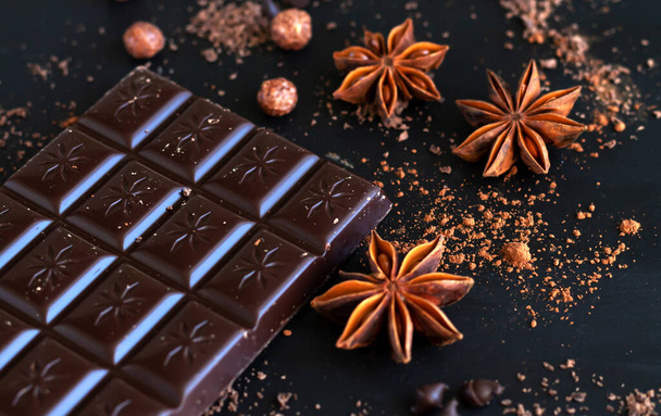 Dark chocolate bar with spice anise, chocolate flakes and powder close-up - Photo, Image