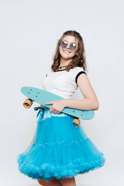 Belle adolescente posant avec penny board sur fond blanc - Photo, image