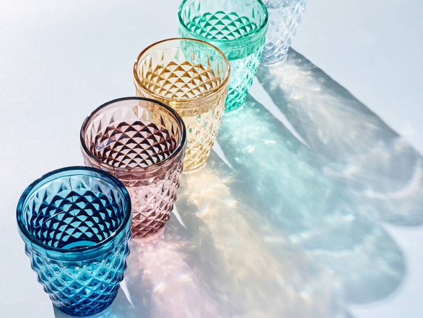 color glasses with water and shadows on a white surface, vertical image - Фото, зображення