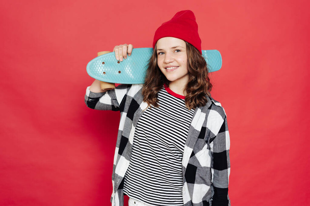 Krásná teenager pózování s penny palubě na červeném pozadí - Fotografie, Obrázek