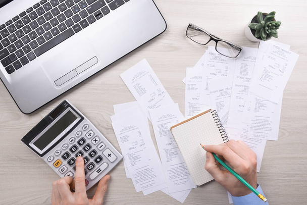 Unrecognizable businessman using calculator on desk office and writing make note with calculate about cost at home office. finance accounting concept. tax , shopping, cost management. - Photo, Image
