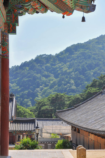 Koreaanse boeddhistische tempel uit Silla-dynastie tijdperk. Uitzicht op bosrijke bergketen met Daeungjeon Hallaan de linkerkant. Haeinsa Temple, Mount Gaya, Gayasan National Park, Zuid-Korea. - Foto, afbeelding