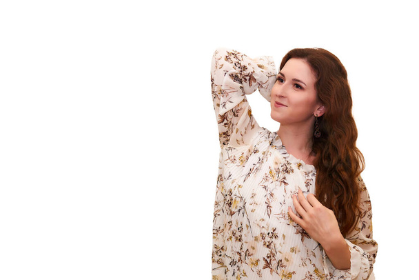 όμορφη νεαρή γυναίκα σε ένα ελαφρύ φόρεμα ονειρεμένα κοιτάζει στο πλάι, απομονωμένη σε λευκό φόντο - Φωτογραφία, εικόνα