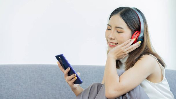 A girl wearing headphones and listening to music on her mobile phone - Foto, immagini