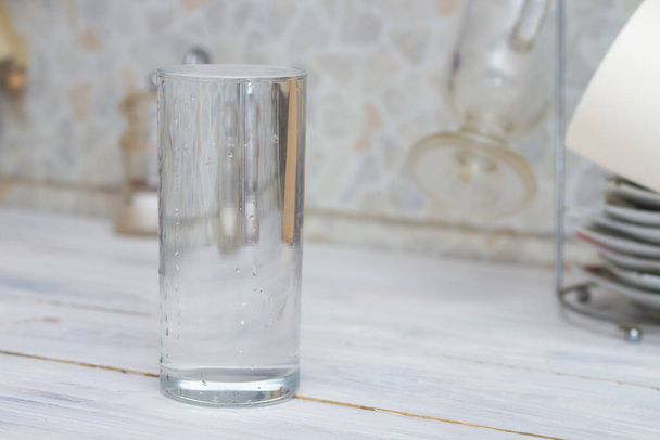 A glass full of clear water sits on the kitchen table. Copy space. - Foto, Bild
