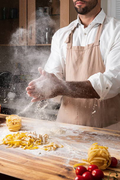 Чоловік шеф-кухар робить італійську локшину тальятелле з тіста на кухні
 - Фото, зображення