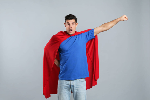 Man wearing superhero cape on grey background - Valokuva, kuva