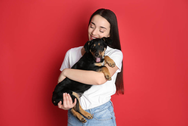 Young woman with cute puppy on red background - Photo, image
