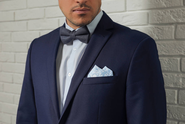 Man with handkerchief in breast pocket of his suit near white brick wall, closeup - Φωτογραφία, εικόνα