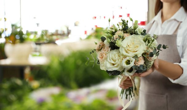 Florist holding beautiful wedding bouquet in flower shop, closeup. Space for text  - Zdjęcie, obraz
