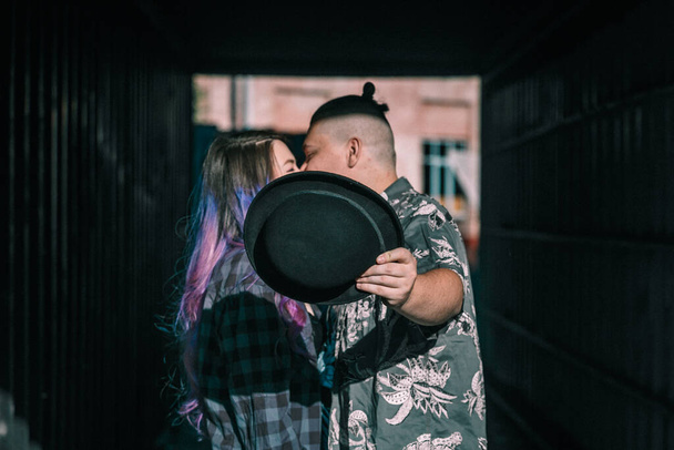 joven pareja besándose mientras cerrando su sombrero. - Foto, Imagen