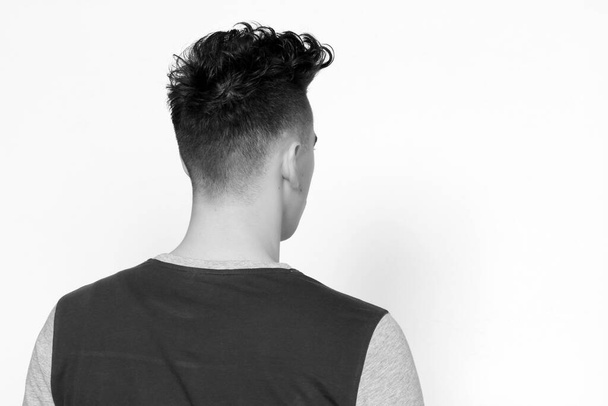 Atrakcyjny model męski z krótkimi włosami pozujący w studio na odosobnionym tle. Styl, trendy, koncepcja mody. - Zdjęcie, obraz