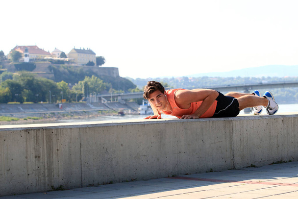 Jovem atleta do sexo masculino exercitando-se junto ao rio Danúbio no cais de Novi Sad, Sérvia. Estilo de vida saudável, corrida ao ar livre, conceito de esportes. - Foto, Imagem