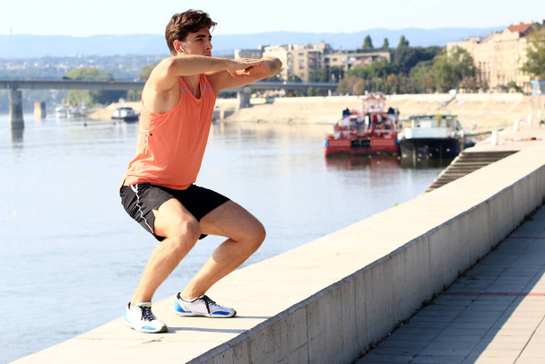 Giovane atleta di sesso maschile che si allena sul fiume Danubio al molo di Novi Sad, in Serbia. Stile di vita sano, corsa all'aperto, concetto di sport. - Foto, immagini