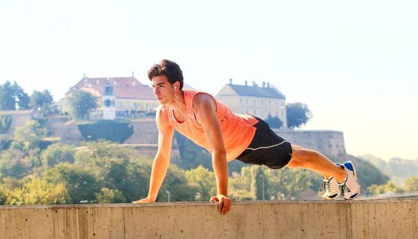 Young male athlete exercising by the Danube river at quay in Novi Sad, Serbia. Healthy lifestyle, outdoor running, sports concept. - Photo, Image