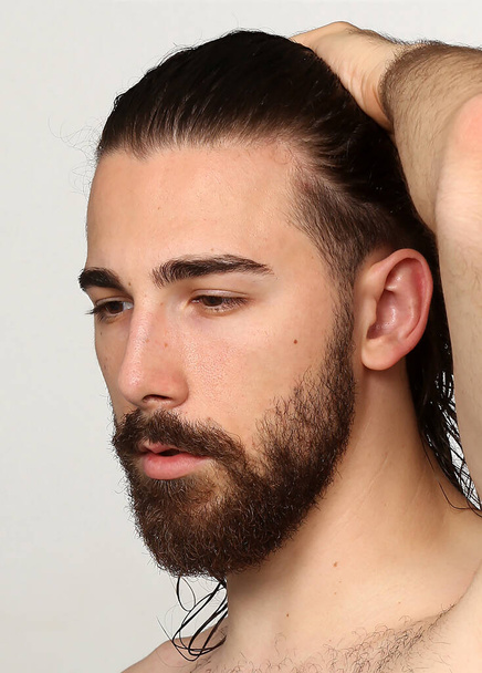 Uzun saçlı ve sakallı çekici erkek model izole bir arka planda stüdyoda poz veriyor. Tarz, trendler, moda konsepti. - Fotoğraf, Görsel