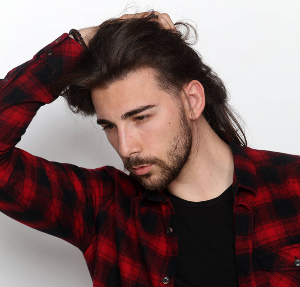 Modelo masculino atraente com cabelos longos e barba posando em estúdio em fundo isolado. Estilo, tendências, conceito de moda. - Foto, Imagem