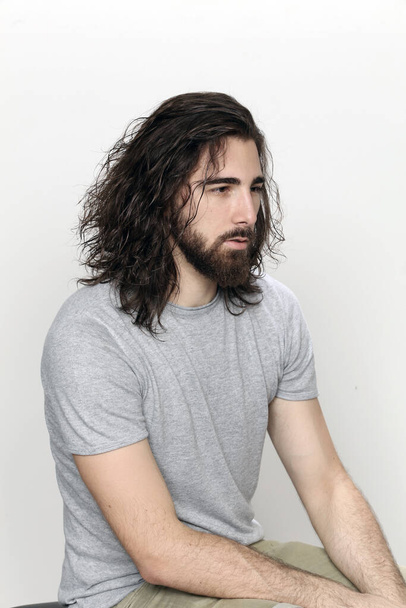 Modelo masculino atractivo con el pelo largo y la barba posando en el estudio sobre fondo aislado. Estilo, tendencias, concepto de moda. - Foto, imagen