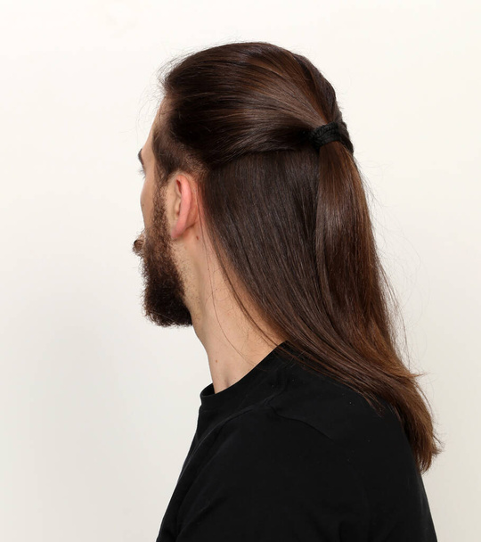 Молода, модна чоловіча модель з довгим волоссям і бородою позує в студії на ізольованому фоні. Мода, бізнес, концепція моделювання
. - Фото, зображення