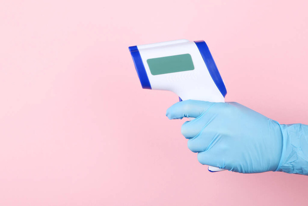 Infrared thermometer in doctor hand on pink background - Foto, imagen