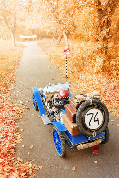 Little boy in the image of a racer finished on an old race car in an autumn park - Photo, Image