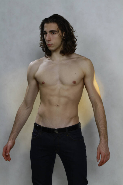 Attractive male model with long hair posing in studio on isolated background. Style, trends, fashion concept. - Fotó, kép