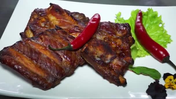 Pieczone żeberka i czerwona papryka chili na białym talerzu - Materiał filmowy, wideo
