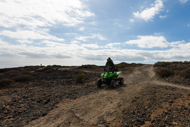 A man riding ATV in sand in protective helmet - Photo, Image