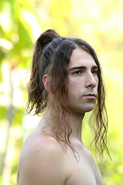 Attraktiver Typ mit sehr langen Haaren posiert in freier Wildbahn. Modellierung und Modekonzept. - Foto, Bild
