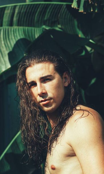 Attractive guy with very long hair is posing in the wild. Modeling and Fashion Concept. - Фото, изображение