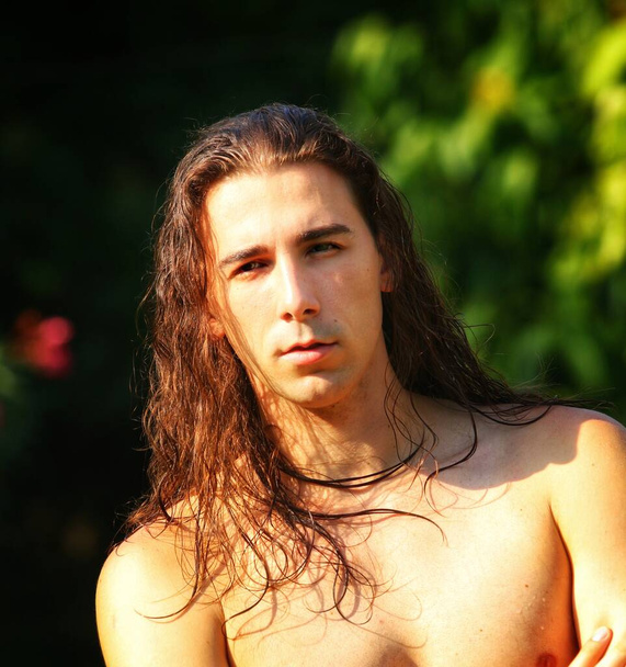 Attractive guy with very long hair is posing in the wild. Modeling and Fashion Concept. - Photo, Image