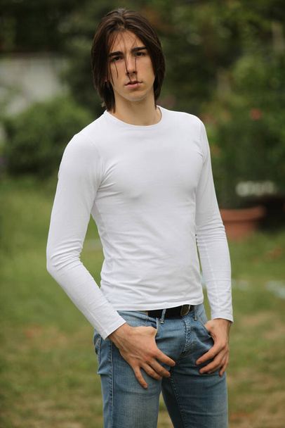 Attractive male model with long hair posing in nature. Style, trends, fashion concept. - Photo, Image