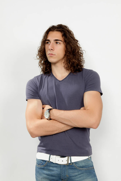 Attractive male model with long hair posing in studio on isolated background. Style, trends, fashion concept. - Photo, image