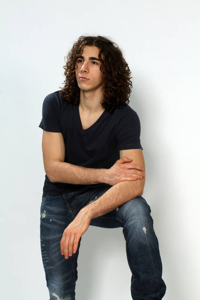 Attraente modello maschile con i capelli lunghi in posa in studio su sfondo isolato. Stile, tendenze, concetto di moda. - Foto, immagini