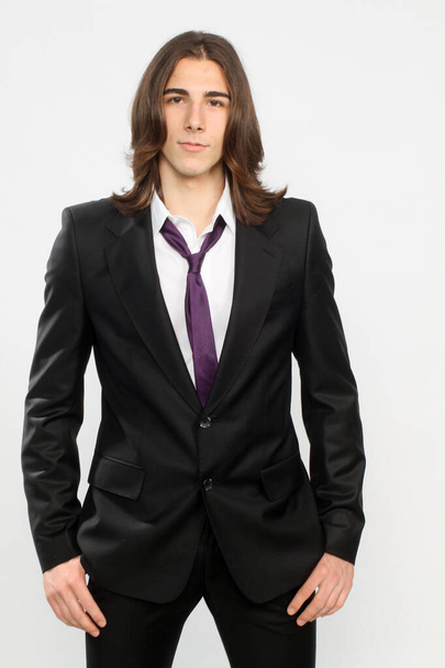 Attraktives männliches Model mit langen Haaren posiert im Studio auf isoliertem Hintergrund. Stil, Trends, Modekonzept. - Foto, Bild