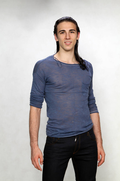 Atrakcyjny model męski z długimi włosami pozujący w studio na odosobnionym tle. Styl, trendy, koncepcja mody. - Zdjęcie, obraz