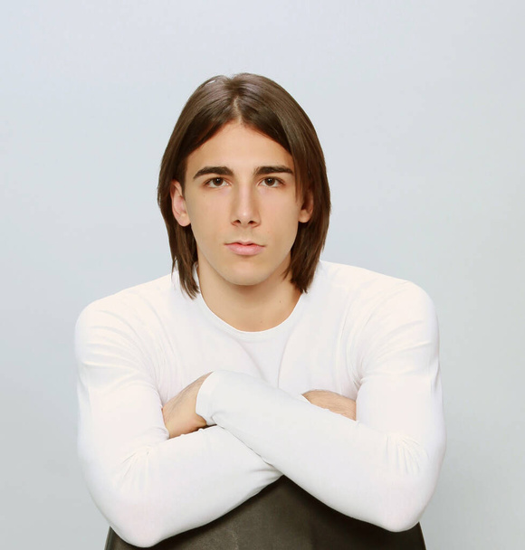 Modèle masculin attrayant avec les cheveux longs posant en studio sur fond isolé. Style, tendances, concept de mode. - Photo, image