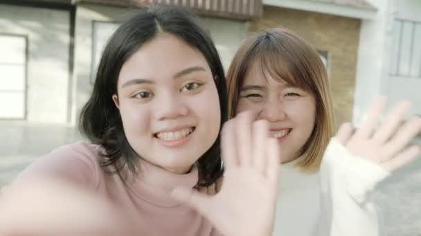 Joven feliz asiático chicas guapas pareja amigo blogger tomar selfie mirar a la cámara con sonrisa cara en la ciudad calle. Primer plano retrato divertido alegres mujeres jóvenes, concepto de vacaciones al aire libre. - Metraje, vídeo