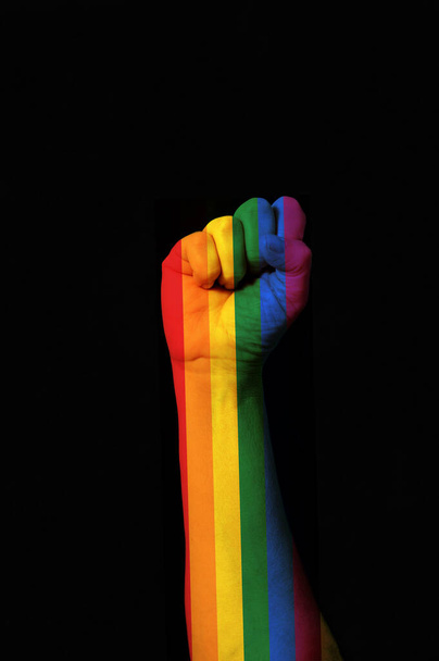 Korotettu nyrkki värillinen sateenkaaren homo ylpeys tumma tausta - Valokuva, kuva