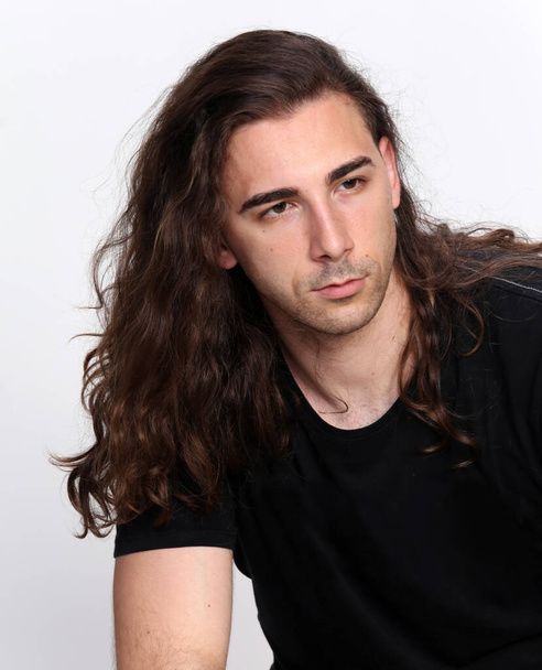 Attractive male model with long hair posing in studio on isolated background. Style, trends, fashion concept. - Fotó, kép