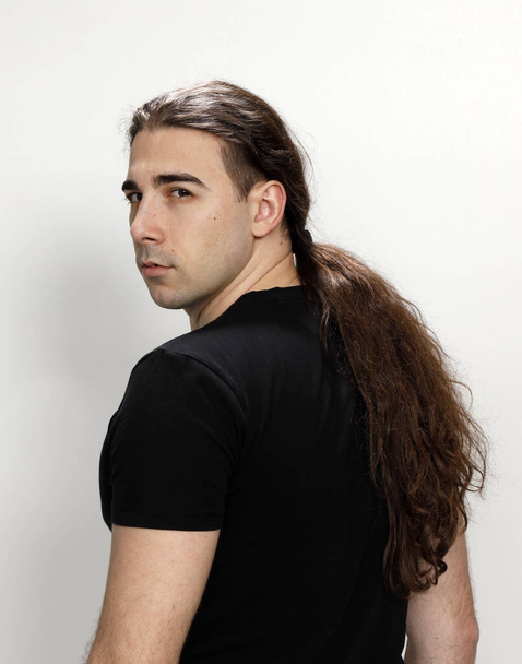 Jovem atraente com cabelo encaracolado muito longo está posando no estúdio. Estilo, tendências, conceito de moda. - Foto, Imagem