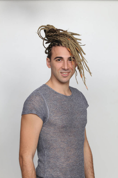 Attractive blonde male model with combination of braids and dreadlocks posing in studio on isolated background. Style, trends, fashion concept. - Foto, Imagem
