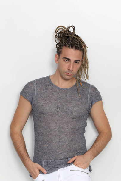 Attractive blonde male model with combination of braids and dreadlocks posing in studio on isolated background. Style, trends, fashion concept. - Foto, Imagen