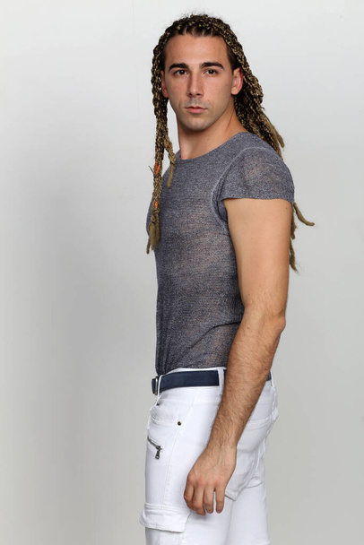 Attractive blonde male model with combination of braids and dreadlocks posing in studio on isolated background. Style, trends, fashion concept. - Foto, afbeelding