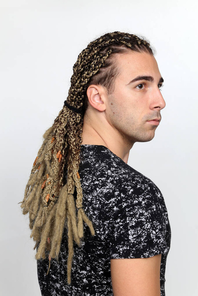 Attractive blonde male model with combination of braids and dreadlocks posing in studio on isolated background. Style, trends, fashion concept. - Photo, Image