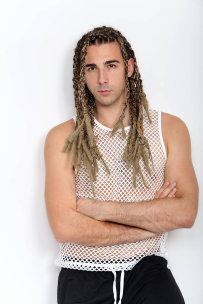 Attractive blonde male model with combination of braids and dreadlocks posing in studio on isolated background. Style, trends, fashion concept. - Photo, image