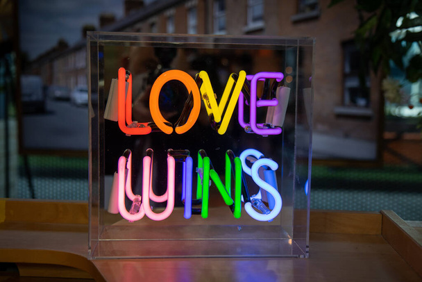 Un letrero de neón de colores brillantes que dice ama gana - Foto, imagen